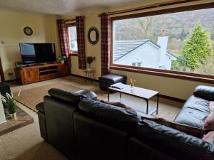 a living room with a couch and a large window at Wilmar Lodge in Arrochar