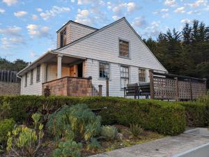 a white house with a bench in front of it at Surfmen's Cottage - Historic Coast Guard property in Point Arena