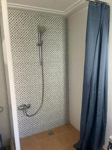 a shower in a bathroom with a blue shower curtain at résidence les meridiennes tiguert in Agadir
