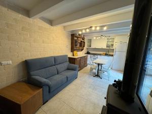 sala de estar con sofá azul y cocina en El Niu de Claravalls, en Claravalls