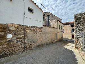 un edificio con una pared de piedra junto a una calle en El Niu de Claravalls, en Claravalls