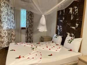 a bedroom with a white bed with red roses on it at PASA LODGE ZANZIBAR in Nungwi