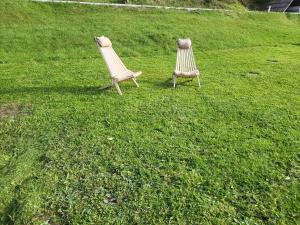 two lawn chairs sitting in a field of grass at Rooms MARETČ in Bohinj