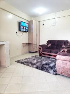 ein Wohnzimmer mit einem Sofa und einem TV in der Unterkunft Sunset suite in Meru