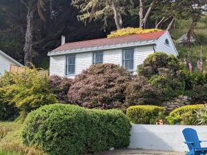 a white house with a red roof and some bushes at Boathouse Cottage (Historic Coast Guard property) in Point Arena