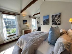 a bedroom with a large bed and two windows at Boathouse Cottage (Historic Coast Guard property) in Point Arena