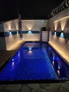 uma grande piscina com luzes azuis em Casa da Lú - Praia e Piscina na Praia Grande