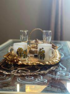 a table with two coffee cups on a gold tray at 3BR Super Lux Apartment Mohandeseen Perfect for Families in Cairo