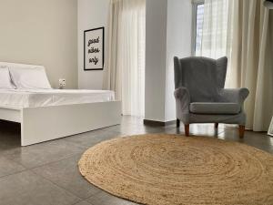 a bedroom with a bed and a chair and a rug at Central, spacious and bright 2-bedroom apartment By Estio Comfort Living in Heraklio