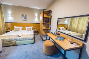 Cette chambre comprend deux lits, un bureau et un miroir. dans l'établissement Hotel Albatros New Town, à Sozopol