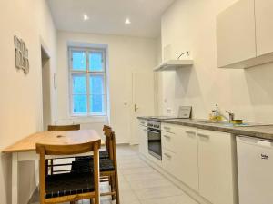 eine Küche mit weißen Schränken und einem Holztisch in der Unterkunft Quiet 60 m2 Apartment with Free Parking in Wien