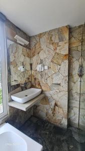 a bathroom with a sink and a stone wall at Quick Stop Inn in Kandy