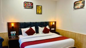 a hotel room with a large bed with red pillows at Ocean Inn in Manāli