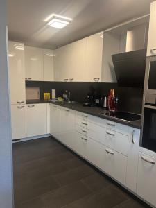 une cuisine avec des armoires blanches et des comptoirs noirs dans l'établissement 2- Zimmer am Bodensee, à Friedrichshafen