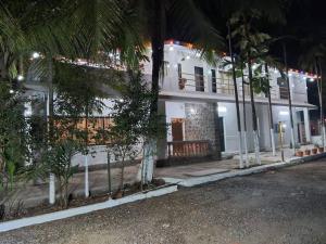 un edificio blanco con palmeras delante en Aanandamay Homestay en Revadanda