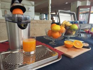 a table with oranges and a juicer and a glass of orange juice at Green Sporting Club Hotel in Alghero