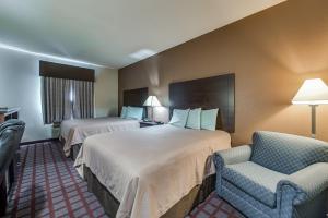 una habitación de hotel con dos camas y una silla en Executive Inn & Suites Cushing, en Cushing