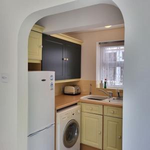 een keuken met een wastafel en een wasmachine bij Cheerful one bedroom home with patio and parking in Newbury