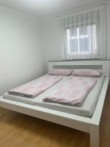 uma cama com lençóis cor-de-rosa e brancos e uma janela em 4 Zimmer Ferienwohnung am Bodensee em Friedrichshafen