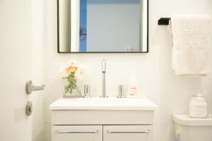 a bathroom sink with a mirror and a vase of flowers at Delta Boutique Loft, en el centro de Salta, p/ 3 in Salta +19 photos