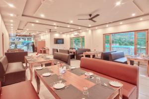a restaurant with wooden tables and chairs and windows at Vivaan stays in Shamshi