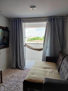 uma sala de estar com um sofá e uma grande janela em Apartamento Villa Giovanne em João Pessoa