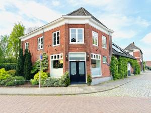 a red brick house with a black door on a street at B&B De Dorpshoeve in Etten