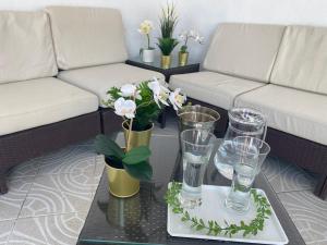 a living room with a couch and a table with glasses and flowers at Hevres El Capricho in Málaga