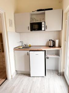 eine Küche mit weißen Schränken und einer Mikrowelle in der Unterkunft Lakeside Apartmanház Soltvadkert in Soltvadkert