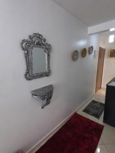 a mirror hanging on a white wall with a bench at Cosy apartement close to the AIRPORT in Tangier