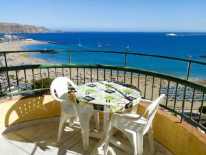 een tafel en stoelen op een balkon met uitzicht op het strand bij Frontal Ocean View Torres del Sol in Los Cristianos