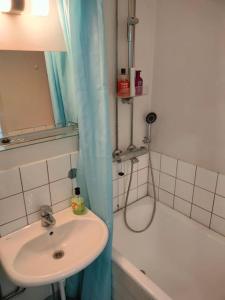 a bathroom with a sink and a bath tub with a shower curtain at Railway&bus station studio in Oulu