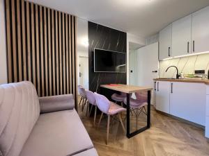 a kitchen and a living room with a table and chairs at Migor Apartamenty in Łeba