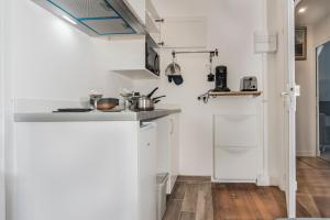 een keuken met witte muren en houten vloeren bij Appartement à Paris-Créteil de 20m2 près du métro 8 mn in Créteil