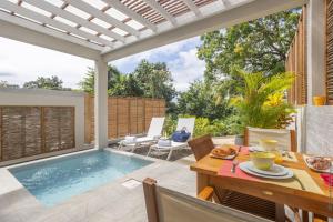 a patio with a pool and a table and chairs at CocoonHuts Residences Martinique in Le Lamentin