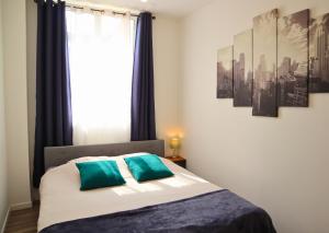 Apart'Moment Saint-Omer Centre في سانت-أومير: غرفة نوم مع سرير ووسائد زرقاء ونافذة