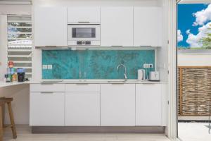 a white kitchen with a sink and a microwave at CocoonHuts Residences Martinique in Le Lamentin