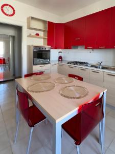 una cocina con armarios rojos y una mesa con sillas rojas en Moonhouse, en Ceglie Messapica