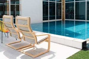 dwa krzesła siedzące obok basenu w obiekcie Rooms Hotel w mieście Dżudda