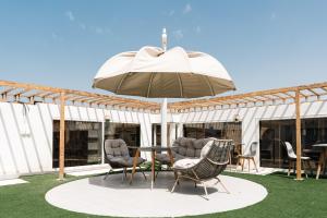 a patio with a table and chairs and an umbrella at Rooms Hotel in Jeddah