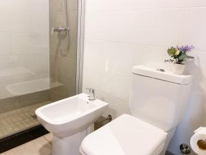 a white bathroom with a toilet and a sink at Alfa Suites en el casco histórico de Salta in Salta