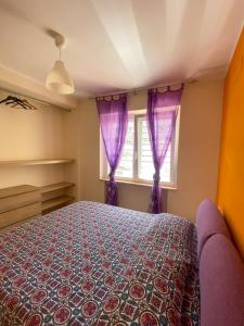 1 dormitorio con 1 cama con cortinas moradas en Villanna, en Sperlonga