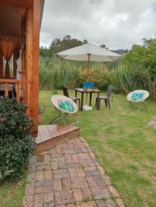 eine Terrasse mit einem Tisch, Stühlen und einem Sonnenschirm in der Unterkunft Cabaña Los Linos in Guasca