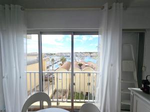 Cette chambre dispose d'un balcon avec des rideaux blancs. dans l'établissement Le Bellevue YourHostHelper, à Gruissan