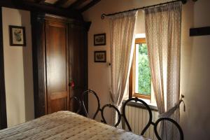a bedroom with a bed with two chairs and a window at Casale Il Mulino con piscina Viterbo Bagnoregio in Celleno