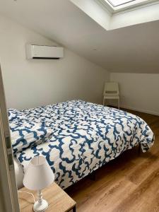 Schlafzimmer mit einem Bett mit einer blauen und weißen Bettdecke in der Unterkunft Duplex 1 chambre in Chalamont
