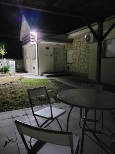 een patio met een tafel en stoelen in de nacht bij Apartman Kućica u cveću in Jagodina