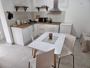 een witte keuken met een witte tafel en stoelen bij Apartman Kućica u cveću in Jagodina
