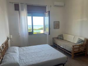 una camera con letto, divano e finestra di Appartamenti in Villa Calamoni a Favignana