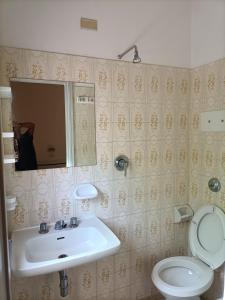 a bathroom with a sink and a toilet and a mirror at HOTEL ROSSINI in Rimini